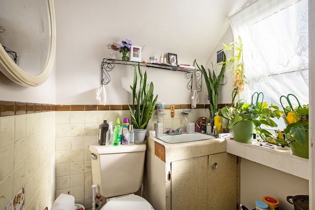 bathroom featuring lofted ceiling, vanity, tile walls, and toilet