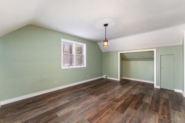 unfurnished bedroom featuring lofted ceiling, a closet, and dark hardwood / wood-style floors