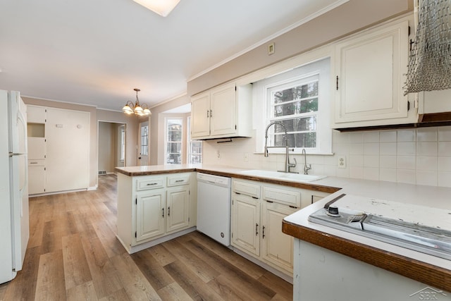 kitchen with pendant lighting, white appliances, sink, tasteful backsplash, and kitchen peninsula