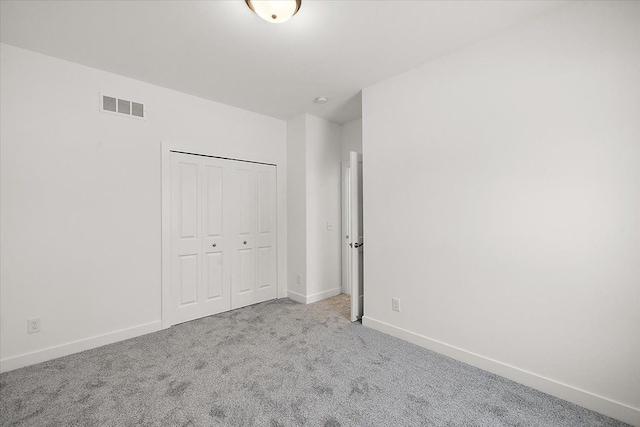 unfurnished bedroom featuring light carpet and a closet