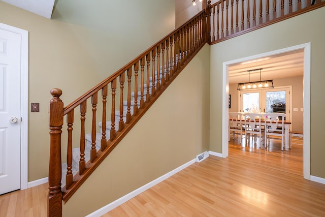 stairs with hardwood / wood-style floors and a chandelier