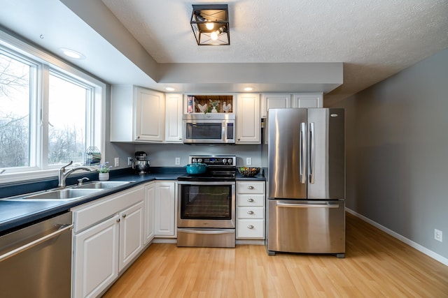 kitchen featuring white cabinets, light wood-type flooring, stainless steel appliances, and sink