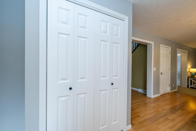 hallway with hardwood / wood-style flooring and a textured ceiling