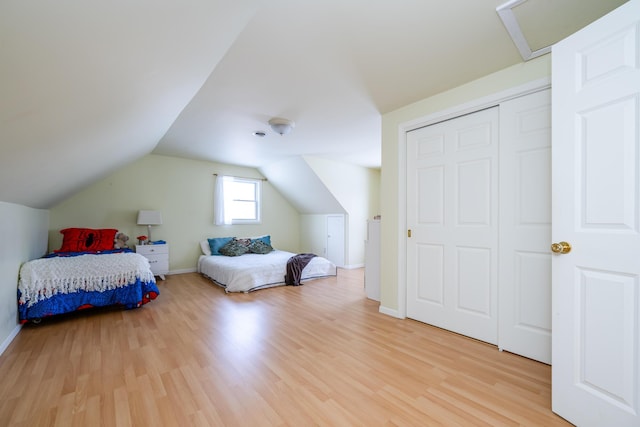 bedroom with hardwood / wood-style flooring, lofted ceiling, and a closet