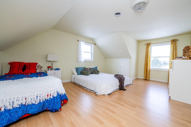 bedroom featuring hardwood / wood-style flooring, vaulted ceiling, and multiple windows