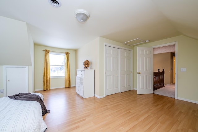 bedroom with light hardwood / wood-style floors, lofted ceiling, and a closet