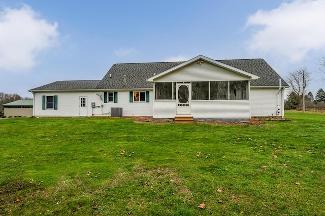 rear view of house with a sunroom, central air condition unit, and a lawn