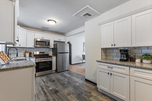 kitchen featuring white cabinets, sink, appliances with stainless steel finishes, tasteful backsplash, and light stone counters