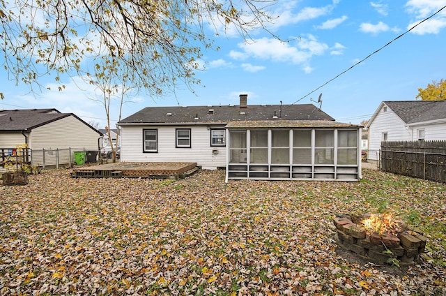 rear view of house featuring a fire pit and a sunroom