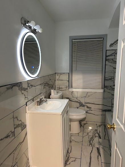 bathroom with vanity, tile walls, and toilet