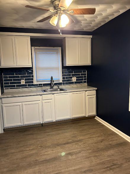 kitchen featuring tasteful backsplash, white cabinetry, sink, and dark wood-type flooring