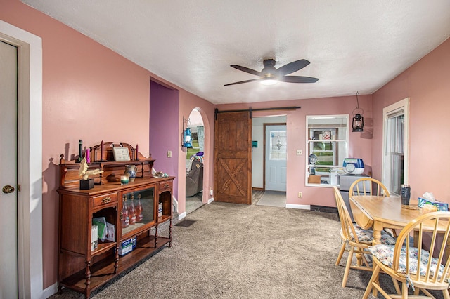 dining area featuring a textured ceiling, a barn door, light colored carpet, and ceiling fan