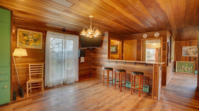 kitchen with a kitchen bar, a notable chandelier, wooden ceiling, and wood walls