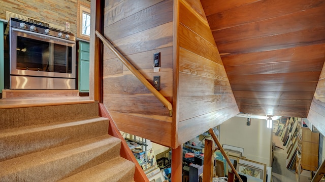 stairway featuring wood walls, wood ceiling, and vaulted ceiling