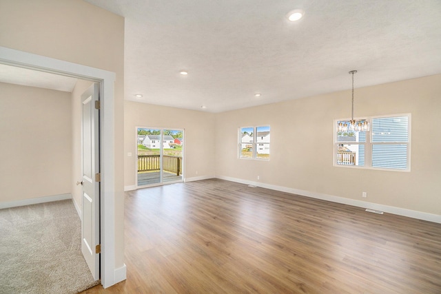 spare room with light wood-type flooring and an inviting chandelier