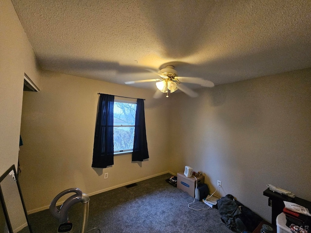 misc room with ceiling fan, dark carpet, and a textured ceiling