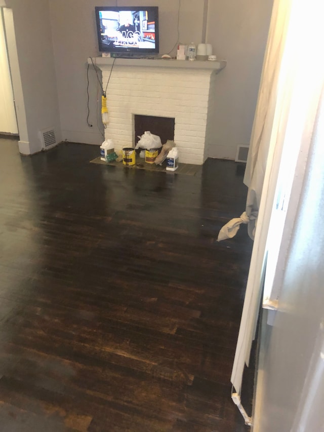 living room with a brick fireplace and dark wood-type flooring