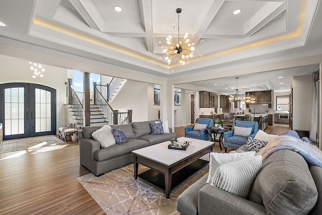 living room with coffered ceiling, an inviting chandelier, french doors, light wood-type flooring, and beamed ceiling