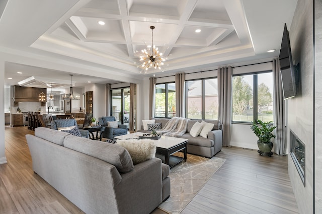 living room featuring beam ceiling, a chandelier, coffered ceiling, and light wood-type flooring