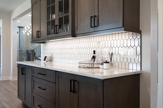 kitchen with dark brown cabinets, light hardwood / wood-style floors, and light stone counters