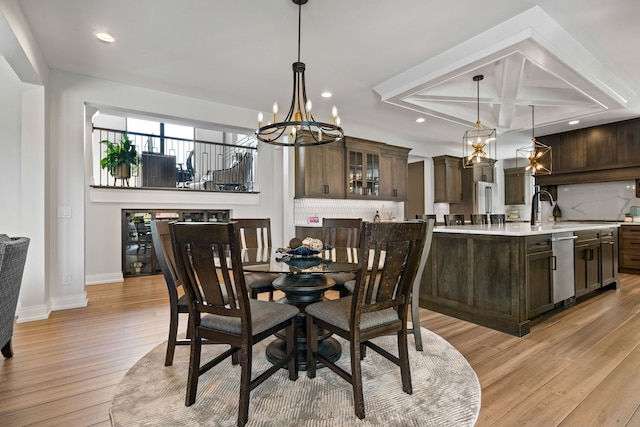 dining space with sink, light hardwood / wood-style floors, and a notable chandelier