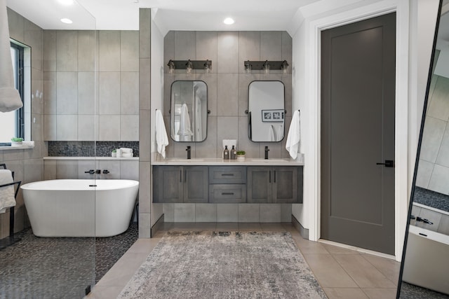 bathroom featuring tile patterned floors, a bathing tub, vanity, and tile walls