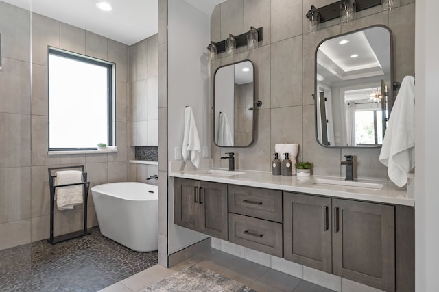 bathroom featuring tile patterned floors, vanity, tile walls, and a washtub