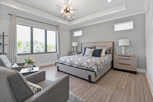 bedroom with a chandelier, a tray ceiling, and light hardwood / wood-style floors