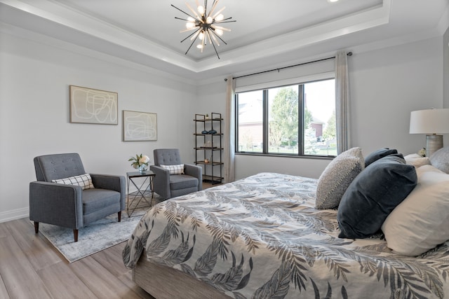 bedroom with an inviting chandelier, a raised ceiling, and light hardwood / wood-style flooring