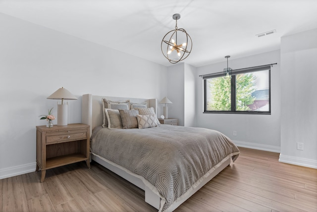 bedroom featuring light wood-type flooring and an inviting chandelier