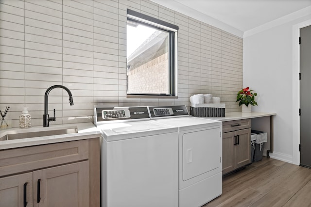 laundry room featuring cabinets, light wood-type flooring, sink, tile walls, and washing machine and dryer