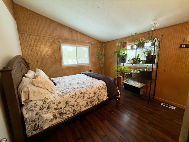 bedroom with lofted ceiling, dark hardwood / wood-style floors, and wooden walls