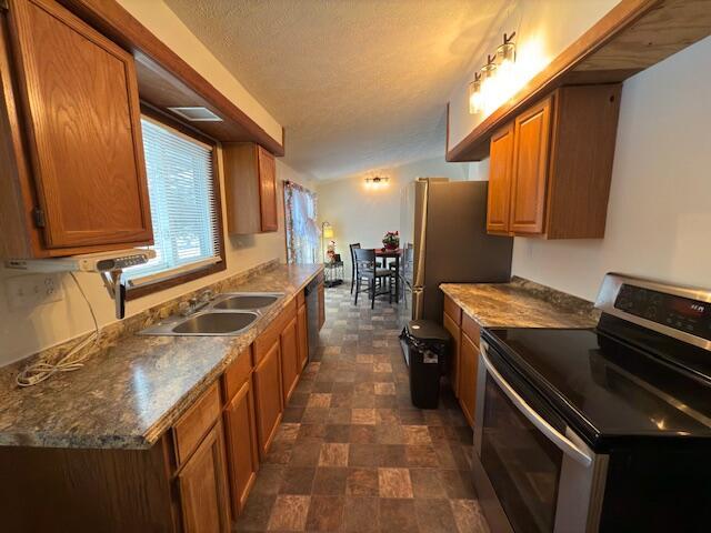 kitchen with appliances with stainless steel finishes, sink, and dark stone counters