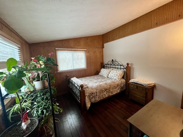 bedroom featuring vaulted ceiling, dark hardwood / wood-style floors, and wood walls