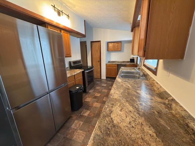 kitchen featuring vaulted ceiling, sink, stainless steel appliances, and a textured ceiling