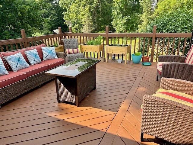 wooden terrace with an outdoor living space with a fire pit