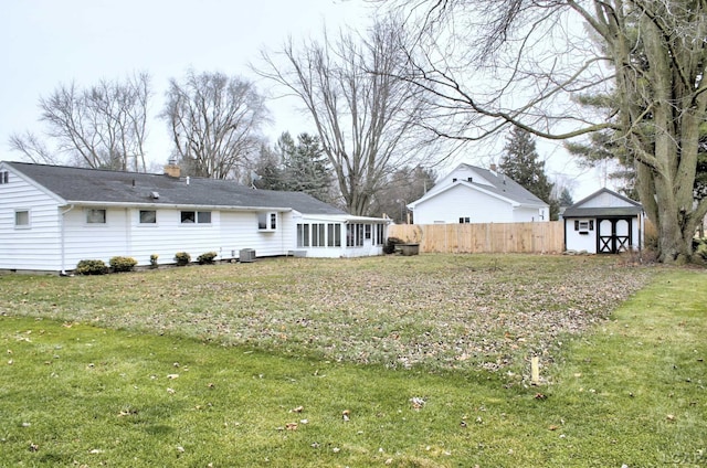 back of house with a sunroom, a yard, central AC, and a storage unit