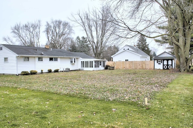 rear view of property with a chimney, fence, an outdoor structure, a sunroom, and a yard