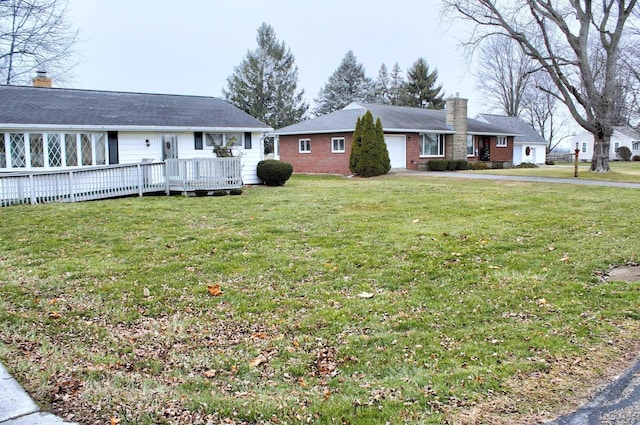 view of yard with driveway, a garage, and a wooden deck