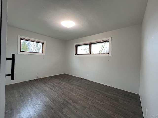 spare room featuring a healthy amount of sunlight and dark hardwood / wood-style floors