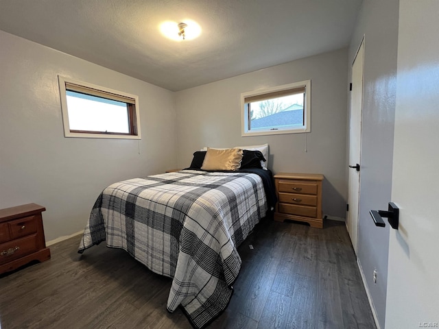 bedroom with baseboards, dark wood-style floors, and multiple windows