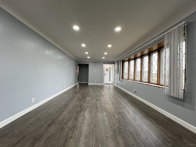 empty room featuring crown molding, dark wood-style floors, recessed lighting, and baseboards