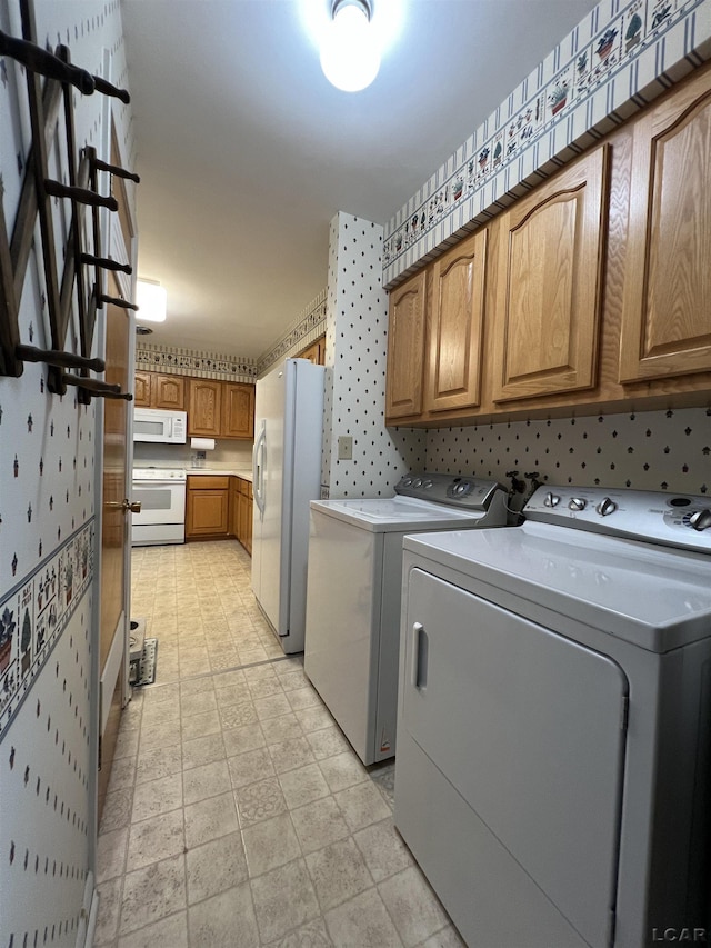 clothes washing area with washing machine and clothes dryer and cabinet space