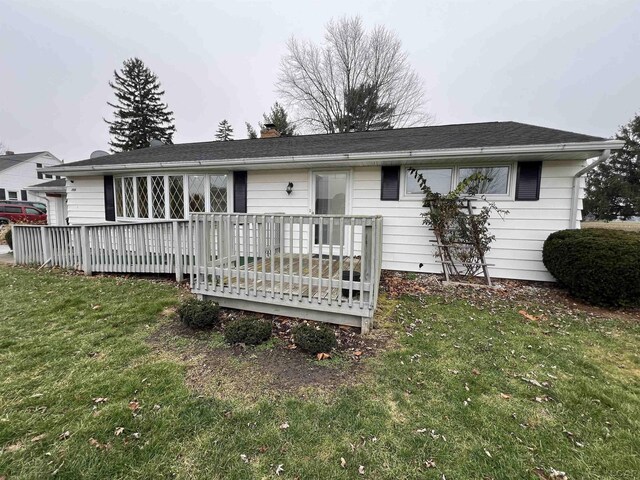 rear view of property featuring a deck and a lawn