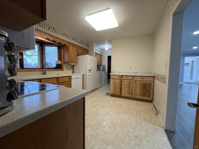 kitchen featuring white appliances, wallpapered walls, light floors, a sink, and washing machine and dryer