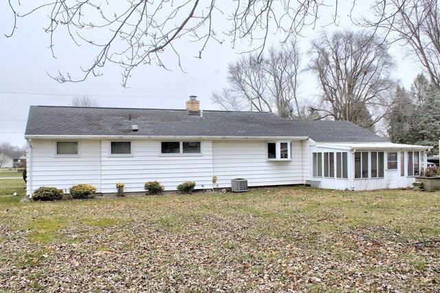 rear view of property featuring central AC unit, a sunroom, and a lawn