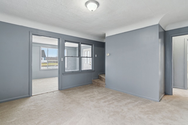 unfurnished room with light colored carpet and a textured ceiling