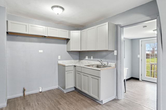 kitchen featuring white cabinets, light wood-type flooring, and sink