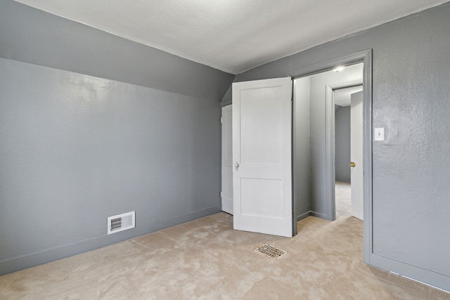 unfurnished bedroom featuring light carpet and vaulted ceiling