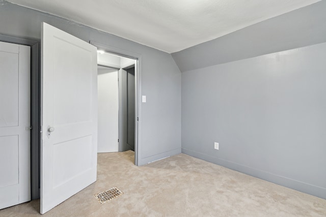 unfurnished bedroom with light colored carpet and lofted ceiling